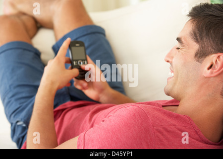 Mann auf Sofa SMS Stockfoto