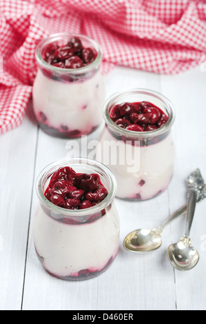 Fruchtdessert mit Kirsche in Gläsern über weißem Holz Hintergrund Stockfoto