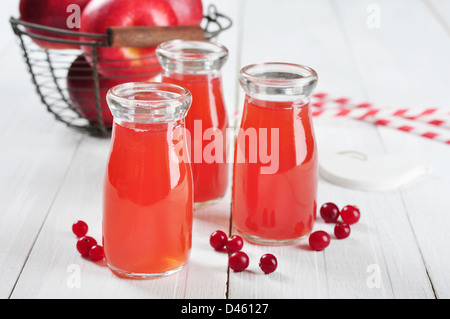 Cranberry-Saft in Gläsern und frische Äpfel in Vintage Korb auf einem weißen Hintergrund Holz Stockfoto