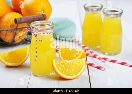 Orangensaft in Gläsern und frischen Orangen in Vintage Korb auf einem weißen Hintergrund Holz Stockfoto