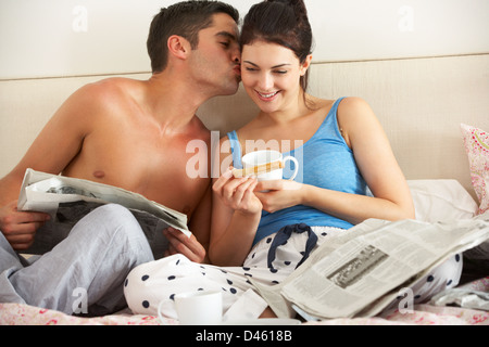 Paar frühstücken und Zeitung im Bett lesen Stockfoto