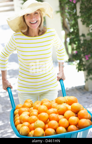 Ältere Frau schob Schubkarre gefüllt mit Orangen Stockfoto