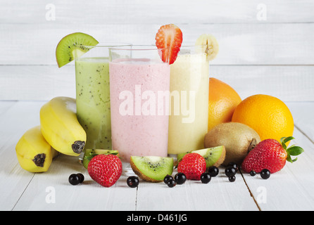 Frucht-Smoothies mit schwarzen Johannisbeeren, Erdbeeren, Kiwi, Orange und Banane auf weißem Holz Hintergrund Stockfoto