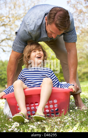 Vater mit Sohn sitzen im Wäschekorb Stockfoto