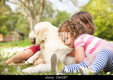 Zwei Kinder streicheln Familienhund In Sommerwiese Stockfoto