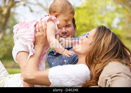 Eltern mit Babymädchen sitzt im Bereich der Sommerblumen Stockfoto