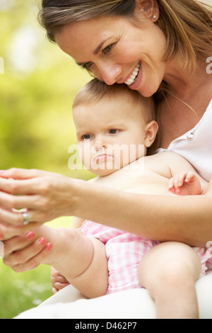 Mutter mit Babymädchen im Bereich der Sommerblumen Stockfoto