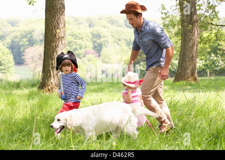 Vater spielen, spannenden Abenteuer-Spiel mit Kindern und Hund In Sommerwiese Stockfoto