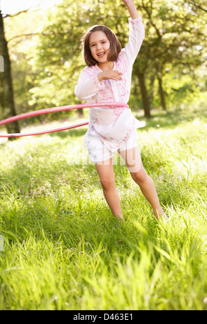 Junge Mädchen spielen mit Hula-Hoop In Sommerwiese Stockfoto