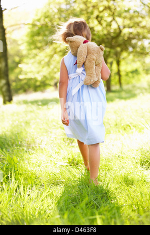 Junge Mädchen zu Fuß durch Sommerwiese mit Teddybär Stockfoto