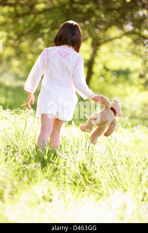 Junge Mädchen zu Fuß durch Sommerwiese mit Teddybär Stockfoto