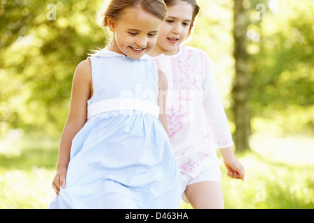 2 junge Mädchen zu Fuß durch Sommerwiese zusammen Stockfoto