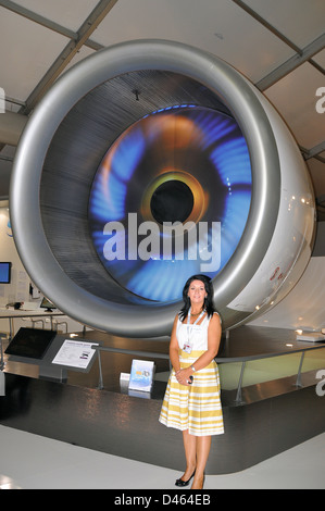 Die Verkäuferin steht vor einem Rolls Royce Trent 900-Triebwerk, um Größenordnung zu verleihen. Die Motoren der Serie Trent sind in Flugzeugen des Typs Airbus A380 eingebaut Stockfoto