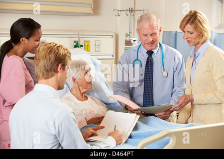 Ärzteteam besuchen ältere Patientin im Bett Stockfoto