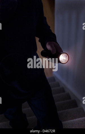 Schattenhafte männlichen Eindringling hält eine Taschenlampe oder Blitzlicht Stockfoto