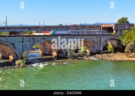 Zug geht über steinerne Eisenbahnbrücke über den Fluss mit grünem Wasser in Moncalieri im Piemont, Norditalien. Stockfoto