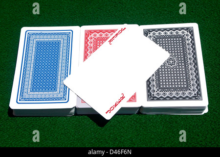 Red Joker liegen über drei verschiedene Farbe Kartendecks am grünen Tisch zu spielen. Stockfoto