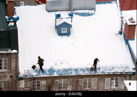 Zwei Männer Schaufeln Schnee vom Dach in Quebec City, Kanada. Stockfoto