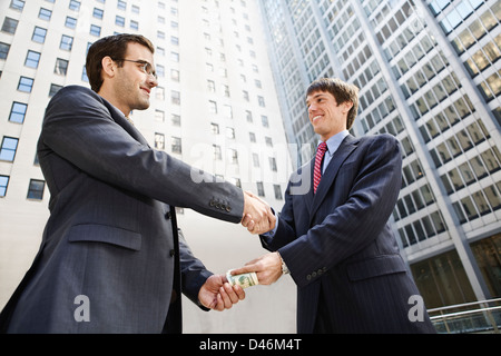 Geldwechsel, die Hände unter einen Händedruck Stockfoto