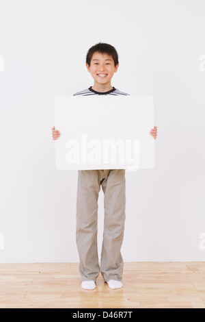 Jungen stehen und hielt eine weiße Tafel Stockfoto