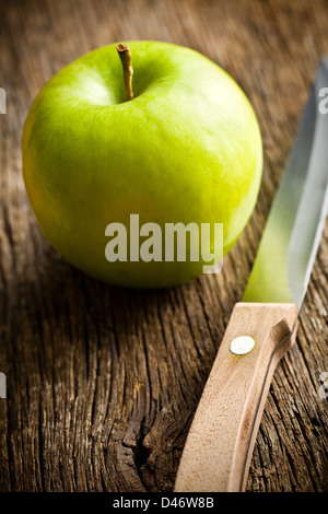 Grüner Apfel mit Messer auf alten Holztisch Stockfoto