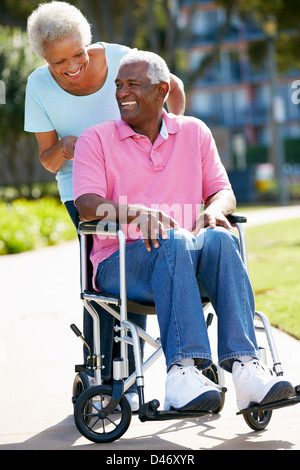 Ältere Frau, die Mann im Rollstuhl schieben Stockfoto