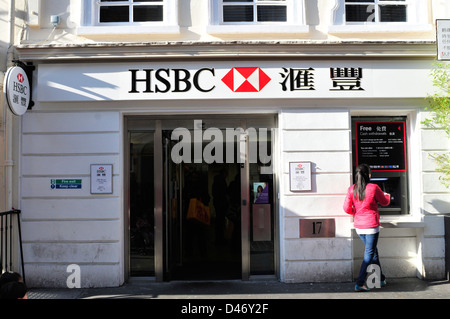 Eine junge Frau nutzt eine Bargeld-Maische in einem HSBC-Niederlassung in China Town, central London, UK. Stockfoto