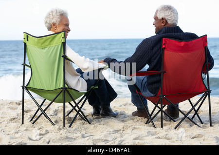 Älteres Paar am Strand im Liegestuhl sitzen Stockfoto