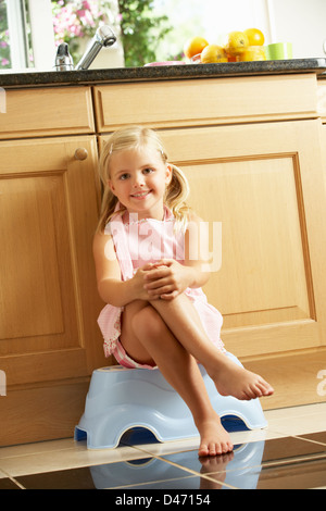 Mädchen sitzen auf Kunststoff Schritt In Küche Stockfoto