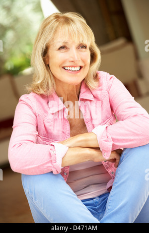 Ältere Frau sitzt vor Haus Stockfoto