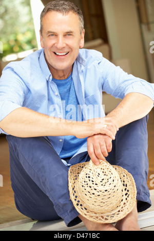 Ältere Mann sitzt vor Haus Stockfoto