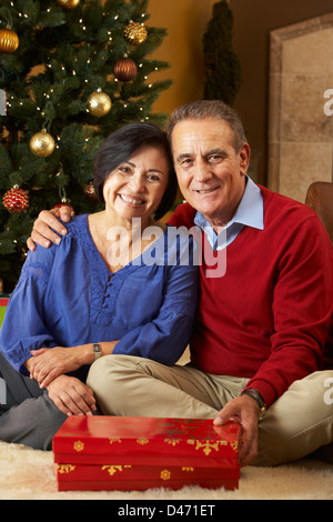 Älteres Paar Austausch von Geschenken vor Weihnachtsbaum Stockfoto