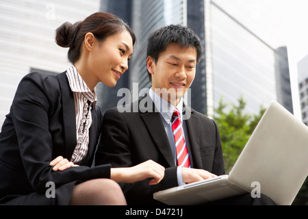 Chinesischer Unternehmer und Unternehmerin auf Laptop draußen Büro arbeiten Stockfoto