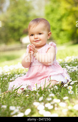 Babymädchen im Sommerkleid im Feld sitzen Stockfoto