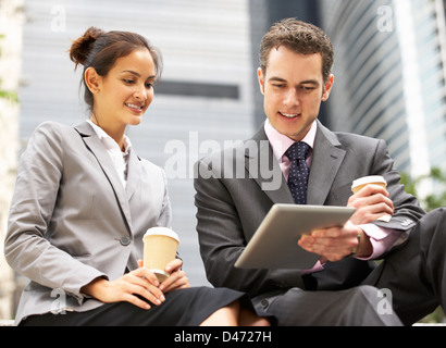 Unternehmer und Unternehmerin mit Digital-Tablette vor Büro Stockfoto