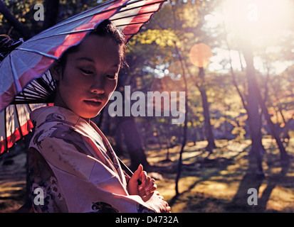 Japan. Outdoor Closeup schöne junge Japanerin Kimono trägt und hält einen Sonnenschirm. Stockfoto