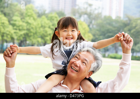 Chinesisch-Großvater geben Enkelin Fahrt auf Schultern im Park Stockfoto