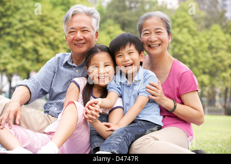 Chinesische Großeltern mit Enkeln im Park sitzend Stockfoto