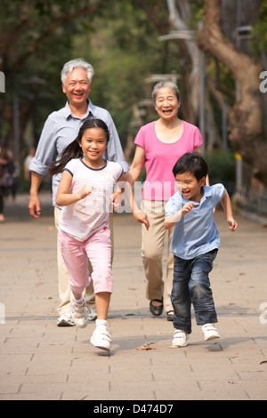 Chinesische Großeltern zu Fuß durch den Park mit fließendem Enkel Stockfoto