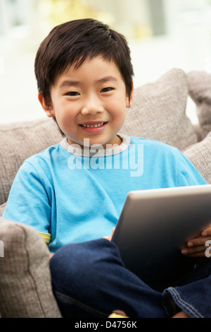 Chinesische junge mit Tablet-PC zu Hause auf dem Sofa sitzend Stockfoto