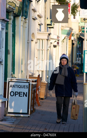 Lady Einkaufsmöglichkeiten vor ein Antiquitätenladen im Winter auf der High Street. Honiton, Devon, UK Stockfoto