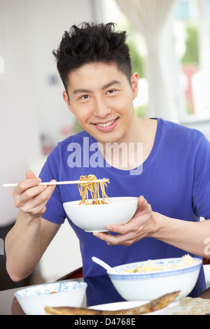 Junge chinesische Mann sitzen zu Hause Essen Mahlzeit Stockfoto