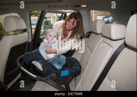 Reife Mutter, Baby Boy in seinem Autositz montiert und mit einem Gurt im hinteren Teil dieses Fahrzeug gesichert. Ältere Mutter Stockfoto