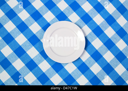 Weiße runde Platte auf blauen aufgegebenes Tischdecke Stockfoto