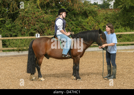 unglückliche Teenager sitzen auf Pferd mit einer Reitstunde Stockfoto