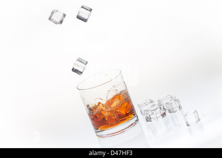 Whisky auf den Felsen spritzte durch fallende Eiswürfel Stockfoto