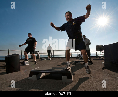 Chief Aircrew Survival Equipmentman Jose Castillo, ein Fitness Instructor, führt eine Step Aerobic auf dem fantail der Nimitz-Klasse Flugzeugträger USS Carl Vinson. Stockfoto