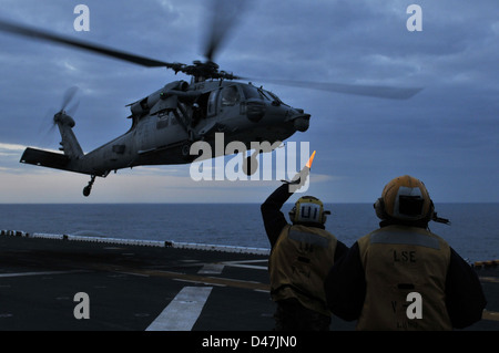 Der Luftfahrt Bootsmann Gehilfen, die aus einem MH-60S Sea Hawk Hubschrauber während Flugbetrieb an Bord der Amphibisches Schiff USS Kearsarge (LHD3). Stockfoto