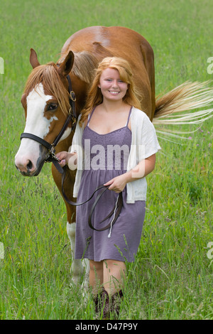 Junge Frau Pferd durch Wiese, eine 18 Jahre alte rote behaarte Reiterin führt. Stockfoto