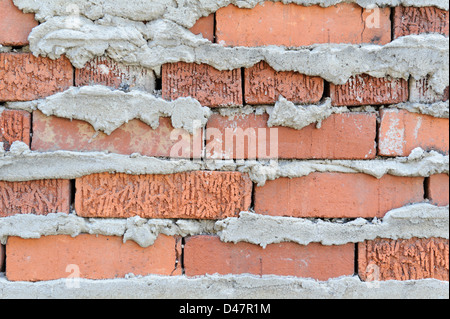 Gemauerte Wand Hintergrund mit schlampig überquellenden Mörtelfugen, die Rückseite der fertigen Wand. Stockfoto